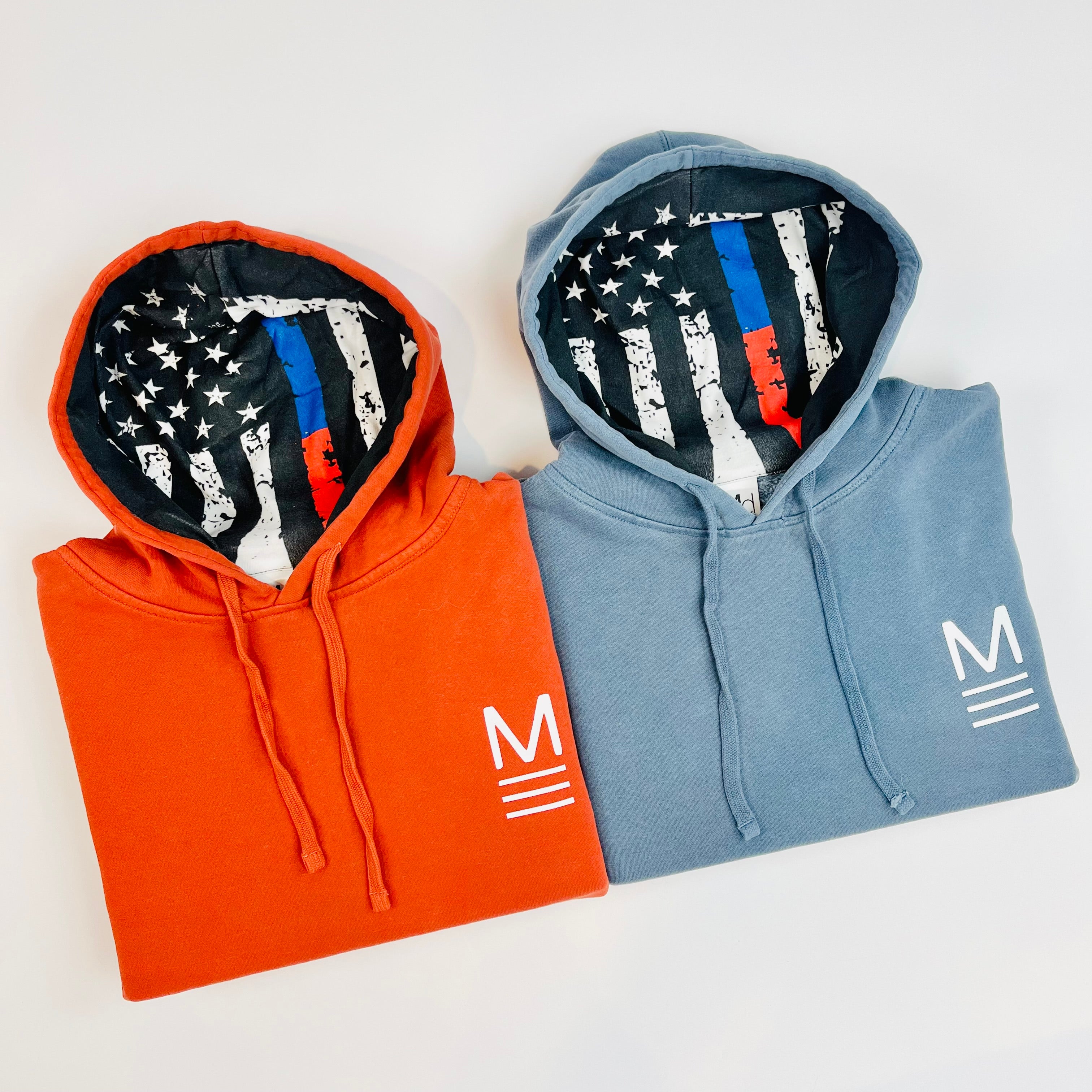 Two hoodies, one red and one blue, with American flag designs on the inside. Line of Duty patriotic hoodie with blue and red flag design