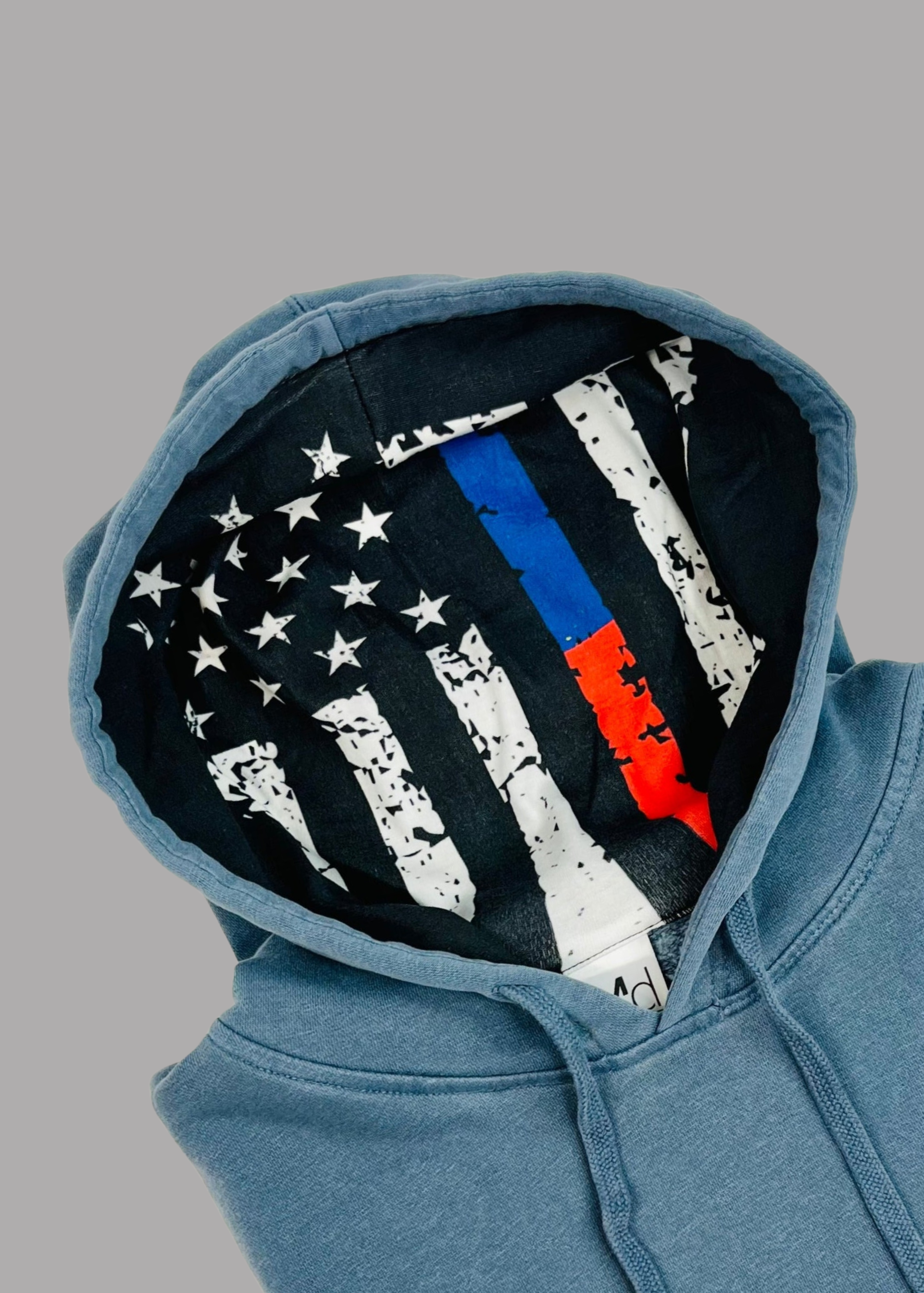 Blue hoodie with a unique flag design on the hood against a gray background
