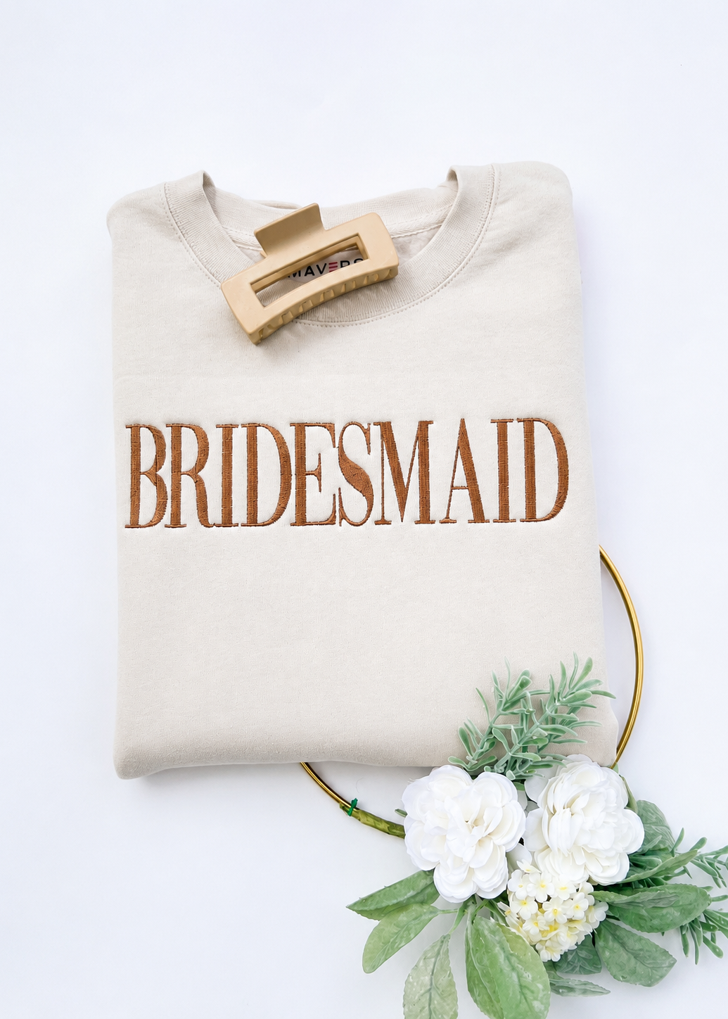 Beige sweatshirt with 'BRIDESMAID' text on a white background with flowers and greenery.