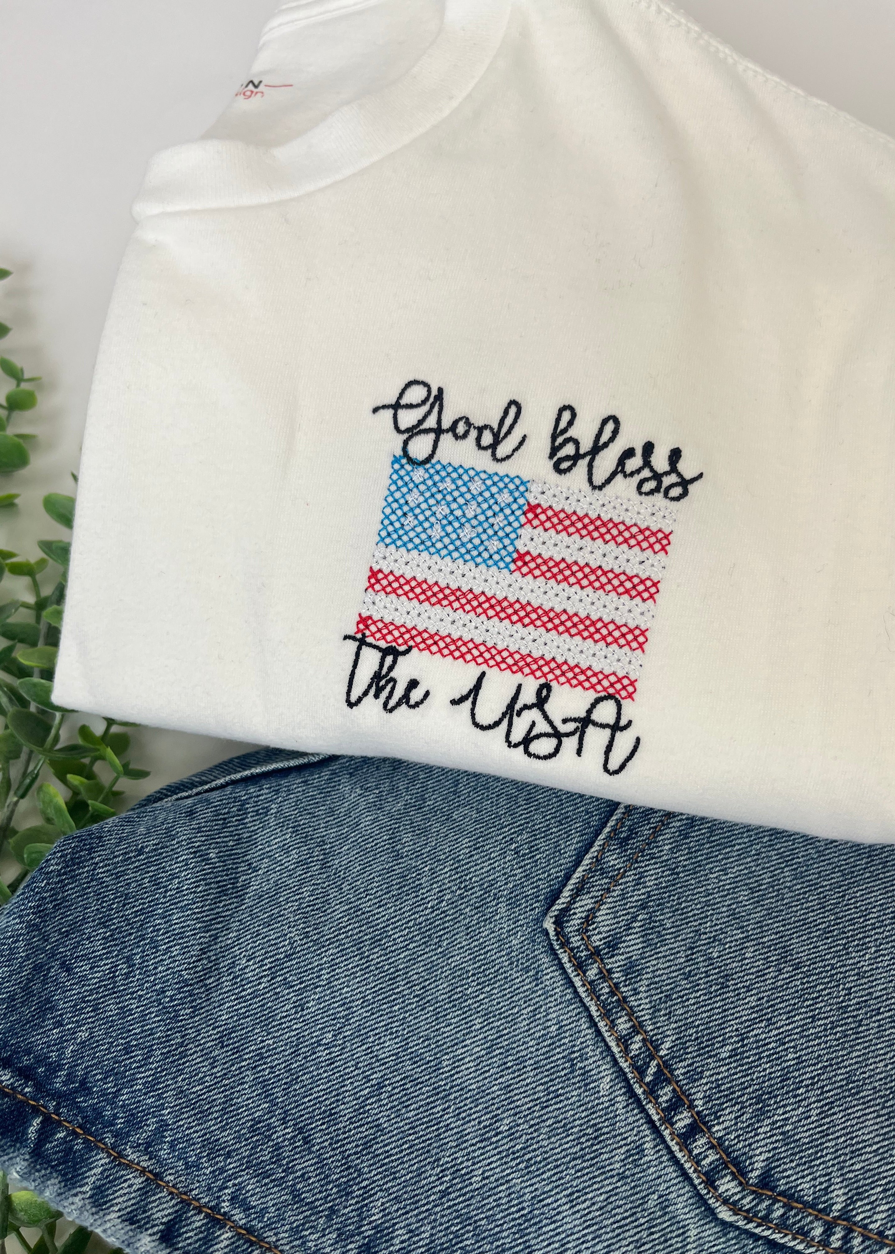 Embroidered design on a white shirt with denim jeans in the background