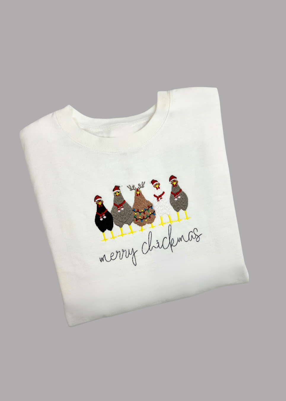 White sweatshirt with 'merry chickimas' text and chicken design on a gray background