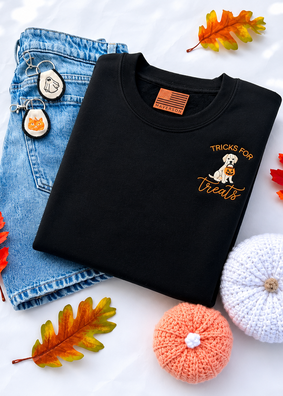 Black sweatshirt with 'Tricks for Treats' design, jeans, and autumn leaves on a white background
