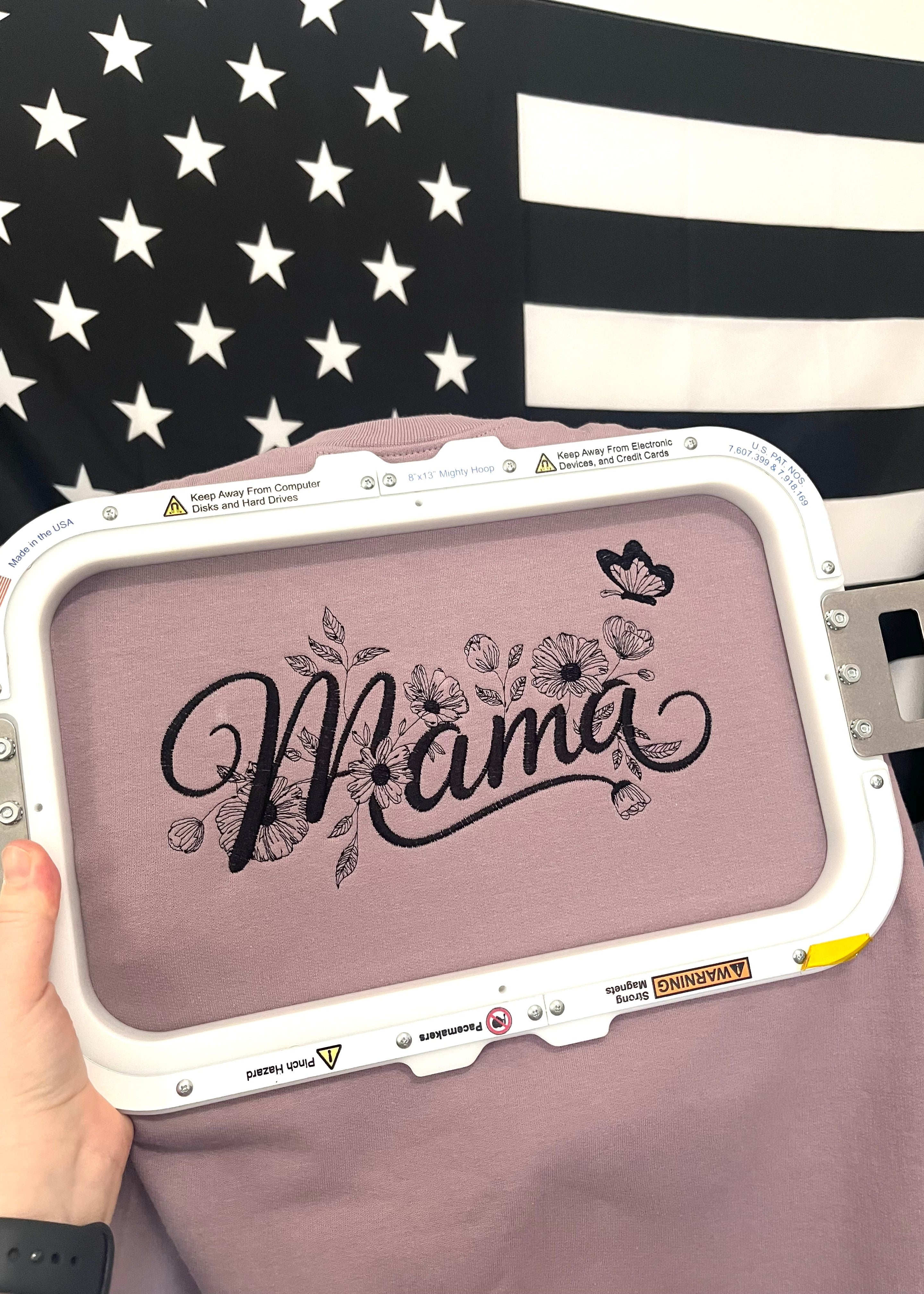Embroidery hoop with 'Mama' design on a flag background