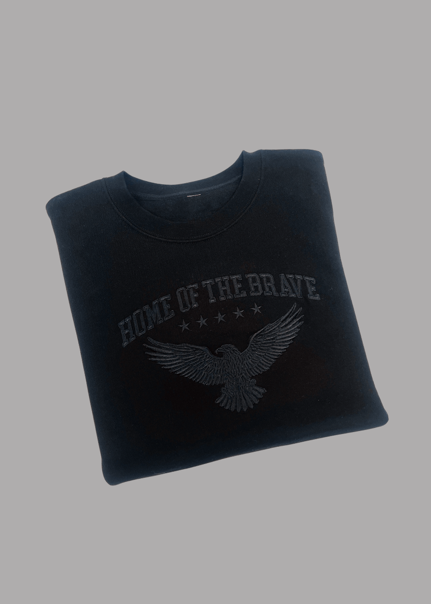 Black sweatshirt with 'Home of the Brave' and eagle design on a gray background
