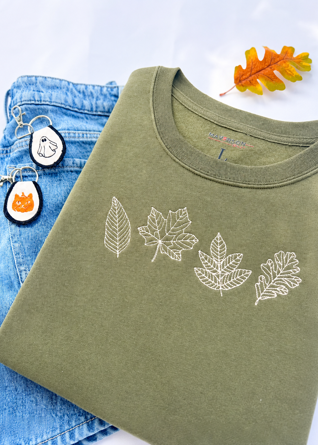Green t-shirt with leaf designs on a blue denim background