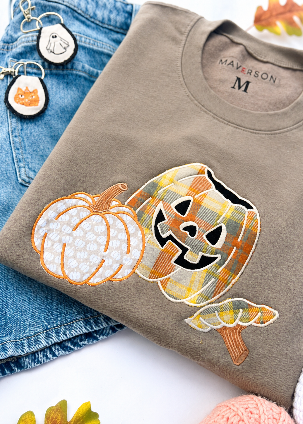 Brown sweatshirt with pumpkin designs on a white surface